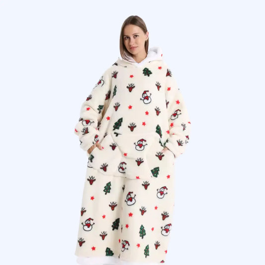A woman modeling a cream-colored fleece hoodie blanket with a festive Christmas print featuring Santa Claus, reindeer, trees, and red stars, set against a solid light blue background.