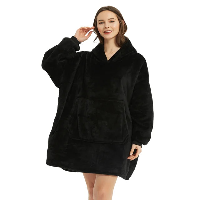 Person cozy in black oversized blanket hoodie.