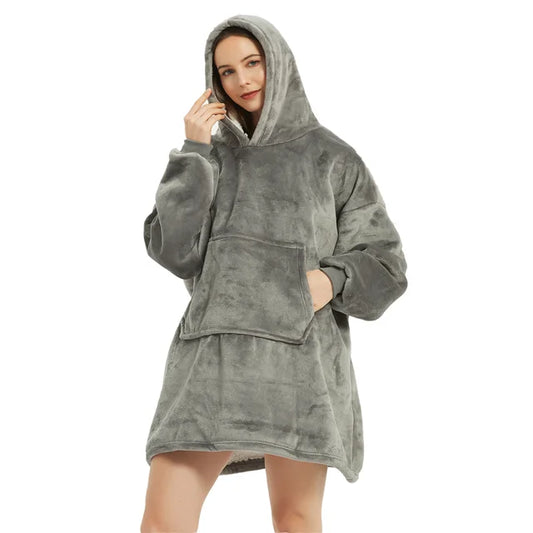 Person cozy in grey oversized blanket hoodie.