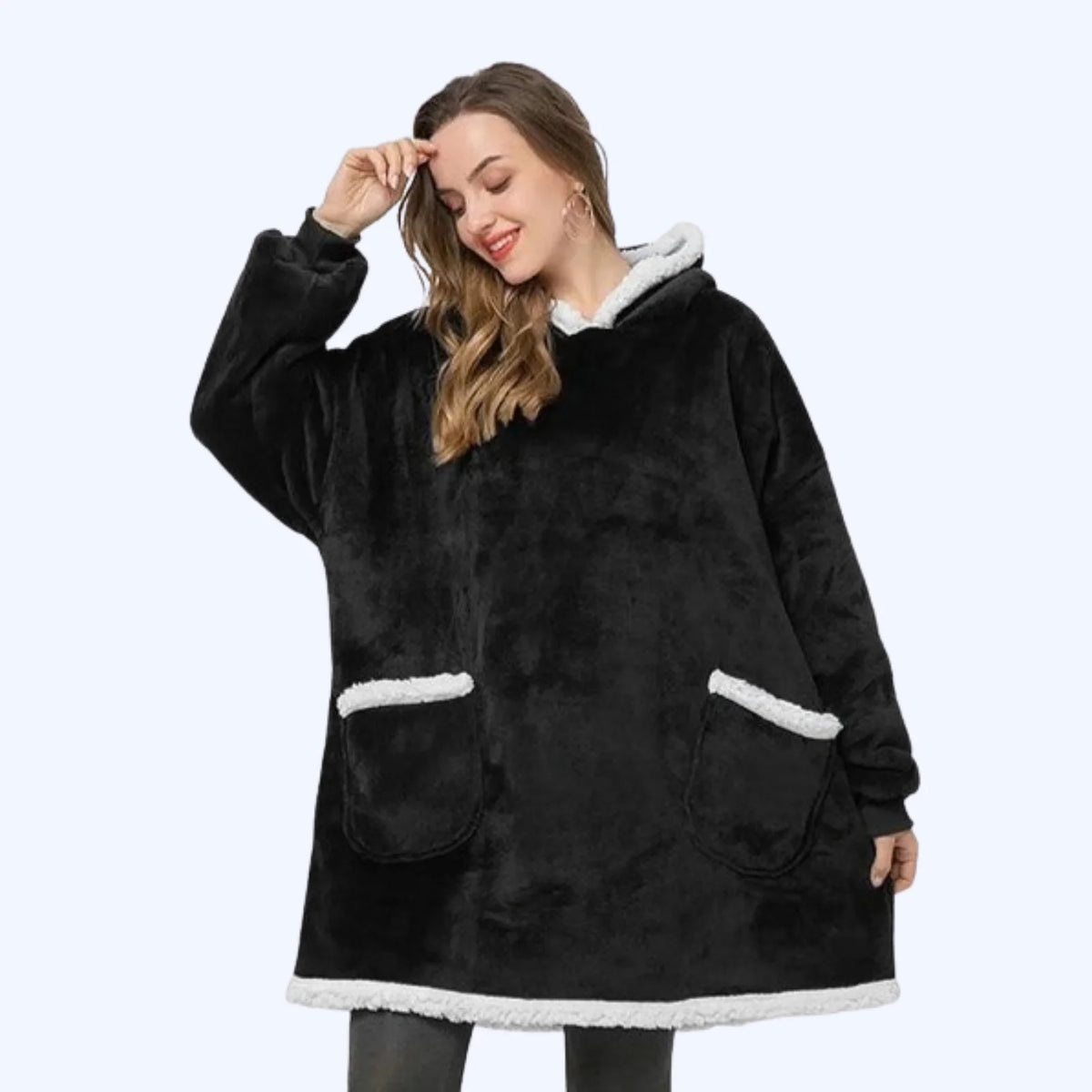 Woman wearing a black hoodie blanket with two pockets and sherpa lining.