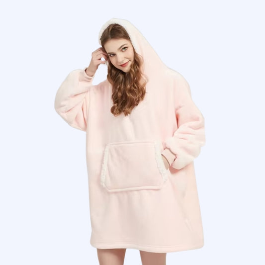 A woman wearing a light pink hoodie blanket with white sherpa lining.