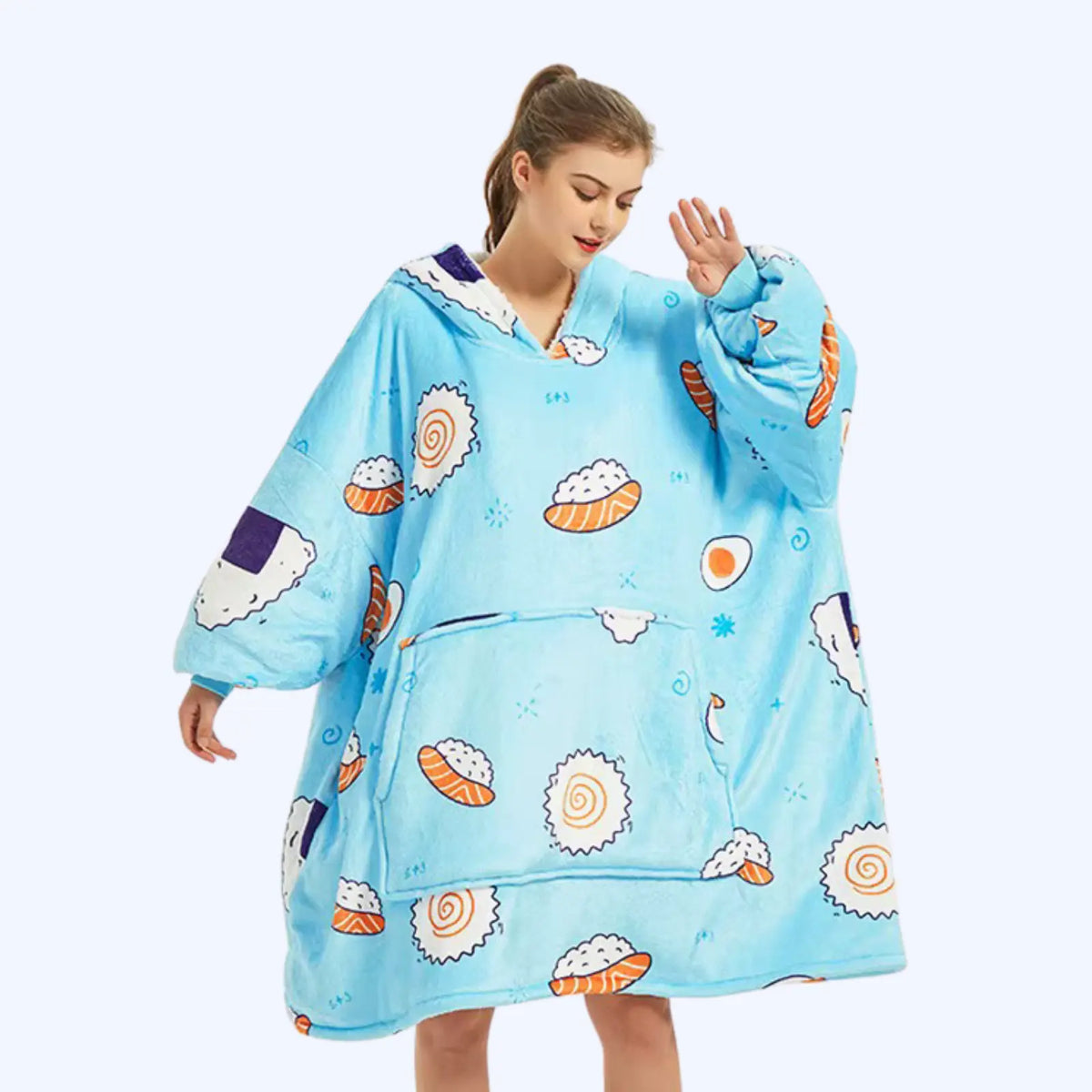 A woman modeling a light blue hoodie blanket with a sushi print, featuring oversized sleeves and a front pocket.