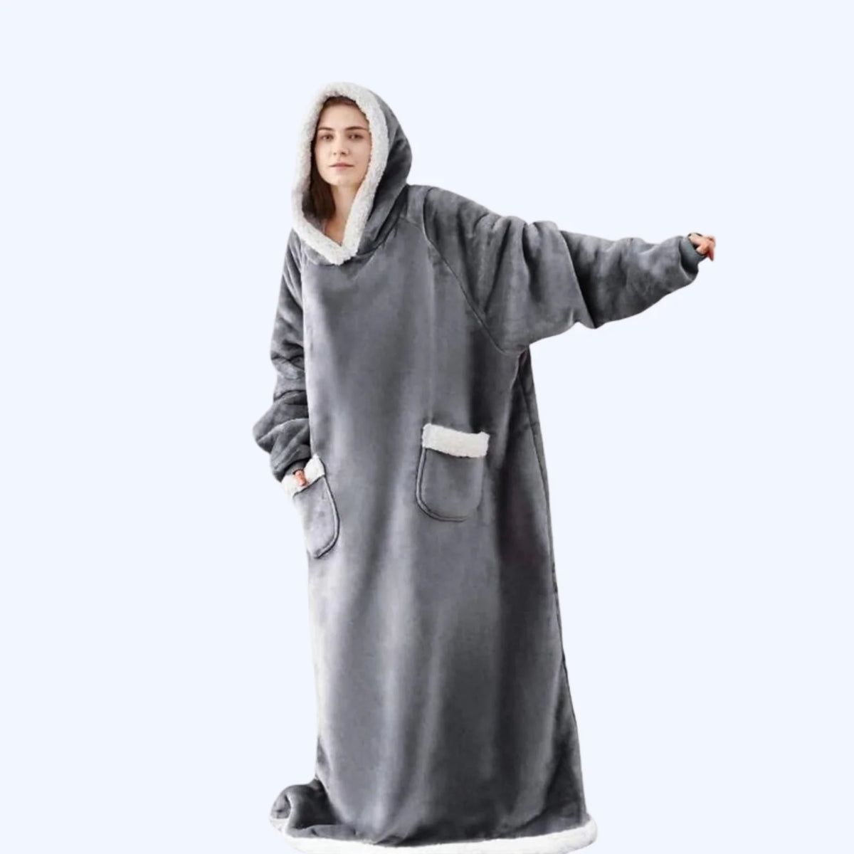 A person wearing a long gray hooded fleece blanket robe with white sherpa lining on the hood, cuffs, and pockets, posed against a light gray studio background.