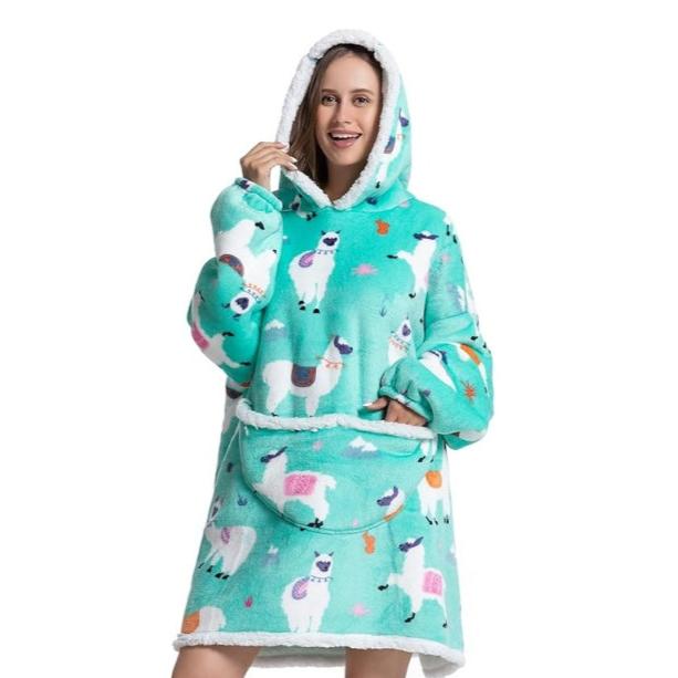 Woman in oversized blanket hoodie with llama pattern. 