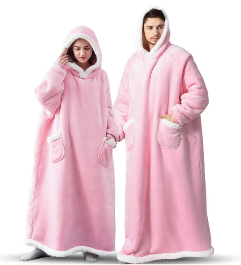 Woman and man wearing pink extra long blanket hoodies that cover from head to toe. 
